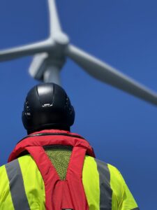 Drone pilot looking up at an offshore wind turbine
