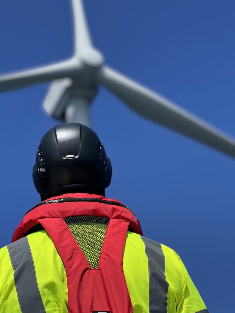 Drone pilot looking up at an offshore wind turbine